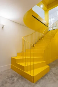 Modern interior with a bright yellow staircase painted with concrete materials.