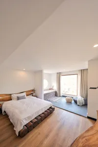 Minimalist bedroom featuring a bed with a wooden headboard and platform, a large window with a view, and a modern design.