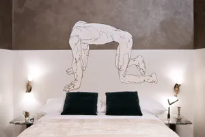 A modern bedroom featuring a wall art painting of a humanoid figure