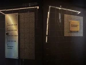 A modern, industrial-style office directory made of metal with a brass finish.