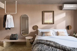 A modern bedroom featuring a bed with white bedding, a brown textured blanket, and mixed materials in the decor, including a 