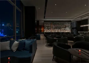 A modern hotel bar with blue fabric couches and black chairs.