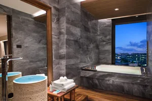 Modern minimalist bathroom featuring a marble tub, sink, and mirror with a cityscape view in the background.