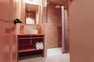 A modern bathroom featuring pink brick tiles and a pink vanity.