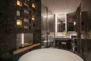 A modern bathroom with dark marble walls and a circular bathtub.