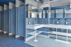 A modern public bathroom with blue tiles and marble accents