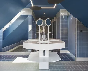Modern public restroom with blue tiles, white sinks, and three circular mirrors.