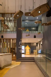 A modern hotel lobby featuring hanging lights, wood, concrete, and glass materials.