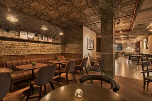 Industrial-style restaurant with brick walls, leather booths, and wooden tables.