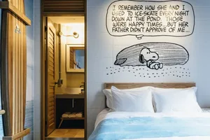 A modern minimalist bedroom with a white wall featuring a Snoopy comic strip