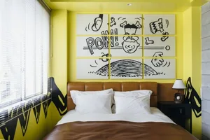 A modern bedroom with yellow walls and brown leather headboard