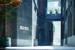 MUJI Hotel exterior with a brick wall and large windows.