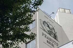 A hotel building exterior featuring brick and concrete materials, with a large mural of a Peanuts character on the side.