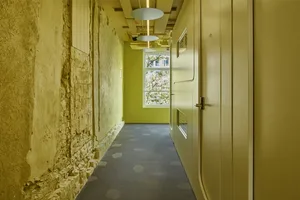 A modern corridor with exposed concrete walls and floor, viewed from inside.