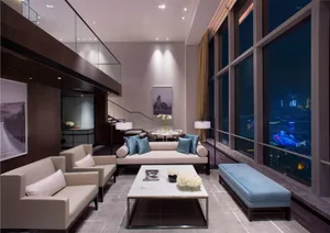A modern living room with fabric seating, glass walls, and metal accents.
