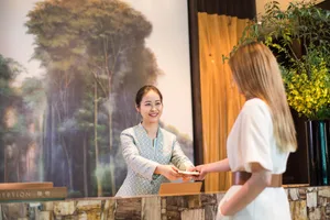 酒店接待櫃檯採用天然石材桌面，微笑的接待員正與客人互動。