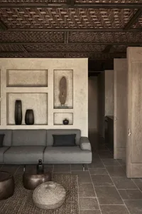 A modern living room with a concrete floor, minimalist furniture, and decorative wall niches filled with large vases.