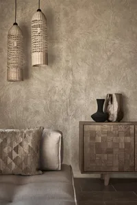 Modern living room featuring textured concrete walls and a wooden cabinet with a mix of baskets and vases.