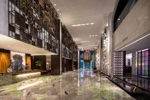 A modern hotel lobby with marble flooring, glass walls, and metallic accents.