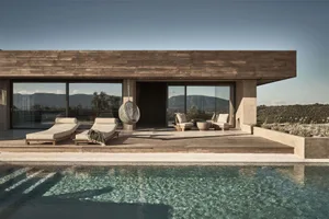 A modern residential space featuring a wooden deck with hanging chairs, a swimming pool, and a view of the mountains.