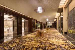 A long, elegant hotel hallway with patterned carpet and wooden accents.