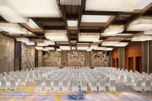 A conference room with multiple rows of white chairs arranged in a single file.