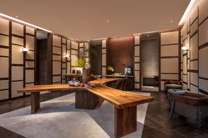 A modern office setting featuring a live-edge wood desk with leather chairs and glass partitions.