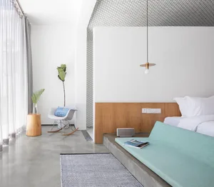 Modern minimalist bedroom featuring a concrete floor, white walls, and wood accents.