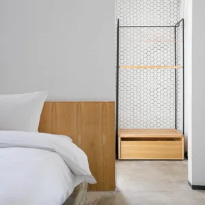 A minimalist bedroom with a white bed, wooden headboard, and modern storage system with an open grid design and built-in benc