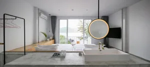 Modern minimalist hotel suite featuring a concrete floor, glass window overlooking the lake, and a circular light fixture.