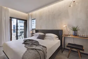 Modern minimalist bedroom featuring a bed with concrete and leather materials.