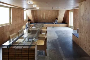 A modern, industrial-style coffee shop with exposed wood walls and concrete flooring.