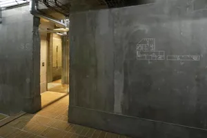 Concrete walls and floor in an industrial-style lobby with a blueprint drawing on the wall.