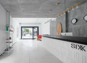 A spacious industrial-style office interior featuring white concrete walls and floors.