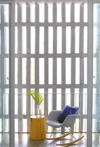 Minimalistic room with a glass and wooden chair and stool, featuring vertical white bars for window design.