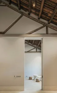 A minimalist attic space with white walls and wooden roof beams.