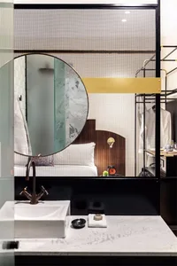 Modern minimalist bathroom featuring metallic accents, glass partitions, and marble surfaces.