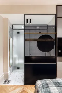 A minimalist bedroom featuring black furniture, glass doors, and a checkered blanket.