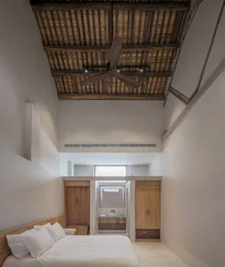 Bedroom with a white bed, wooden ceiling, and minimalist decor.