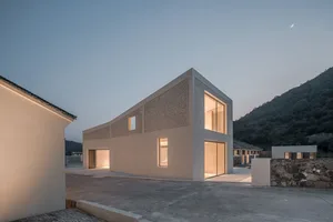 Modern building with concrete facade and large windows at dusk.