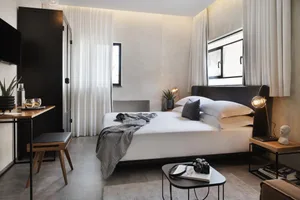 A modern bedroom featuring a white interior with a bed, desk, and various decorative items.