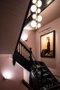 A modern black staircase with a black railing and wooden wall.