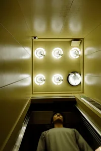 A modern elevator interior featuring circular lighting fixtures made of plastic.