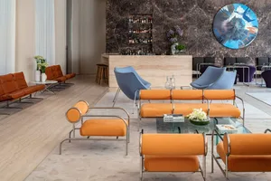 Modern hotel lobby featuring orange leather seating, marble accents, and metal framework.