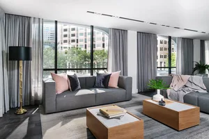 Modern living room with grey couches, large windows, and grey curtains
