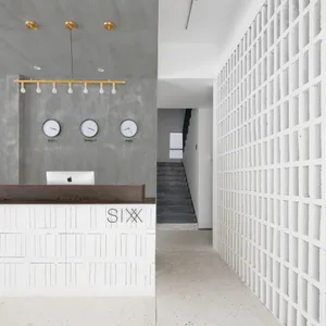A modern minimalist lobby with concrete walls and a reception desk.