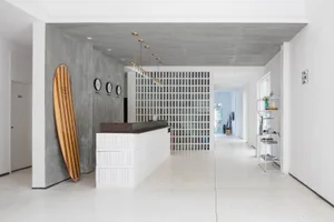 A modern reception area featuring a concrete and white wood desk, with clocks on a dark grey wall.