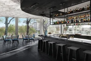 A modern restaurant bar interior with black wooden elements, seating for patrons, and a well-stocked bar.