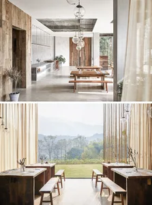 A modern restaurant interior with wooden benches, concrete floors, and a large window overlooking mountains.