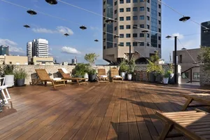 A modern rooftop terrace with wooden decking, featuring outdoor furniture and potted plants.